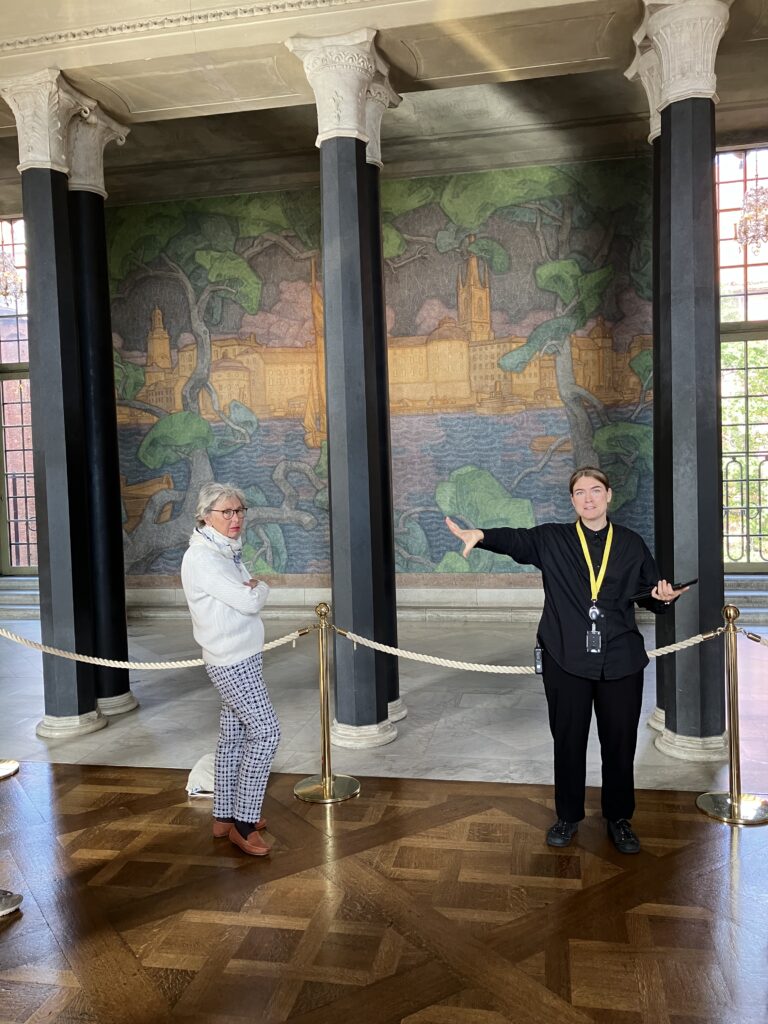 guide och besökare framför Prins Eugens Stockholmsmotiv i Stockholms Stadshus